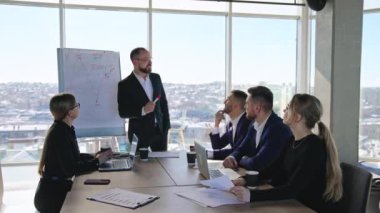 Ofiste iş toplantısı. Yönetici grafikteki eğri hakkında konuşuyor. İş adamları bu fikirleri büyük ışık ofisinde tartışıyor..