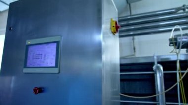Fabrikada süt ürünleri üretimi. Metal kutunun kumandasında ekran var. Yiyecek fabrikası için ekipman.