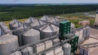 Tarımsal hasat için büyük bir çelik deposu. Büyük silo tankları kompleksinin üzerinde uçuş. Arkaplanda güzel bir yeşillik.