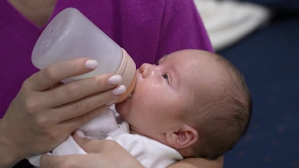 母亲抱着一个孩子 用瓶子喂婴儿 婴儿慢慢地吃着牛奶睡着了 靠近点 — 图库视频影像
