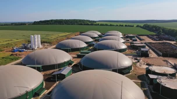 バイオガスの生産のための大きい円形貯蔵タンク ゴミをエネルギーに変えるための革新的なプラント 背景にある農業分野 — ストック動画