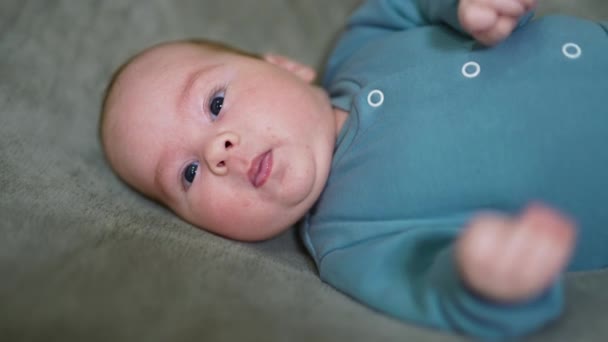甘い赤ん坊はカメラを見つめ 舌を示しています 灰色の背景にあるおかしい子供 クローズアップ — ストック動画