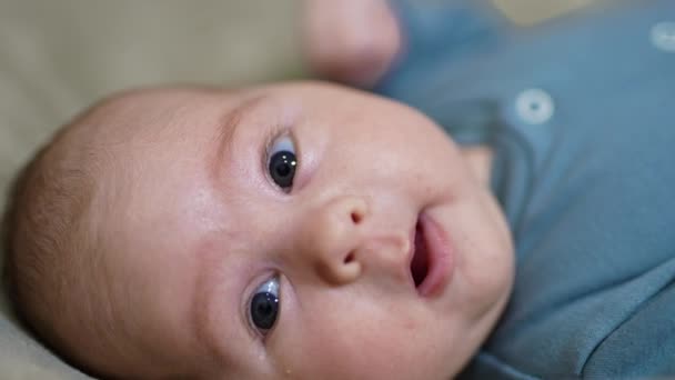 カメラを見つめている愛らしい赤ちゃんの顔 顔の赤ん坊はカメラに向かって頭に横たわっている クローズアップ — ストック動画
