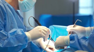 Cerrahların elleri lastik eldivenlerle ameliyat aletlerini tutuyor. Ameliyathanede ameliyat..