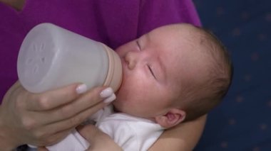 Bebek sütü şişeden yiyor ve uykulu gözlerini kapıyor. Bebek yemek yerken yavaş yavaş uykuya dalıyor. Kapat..