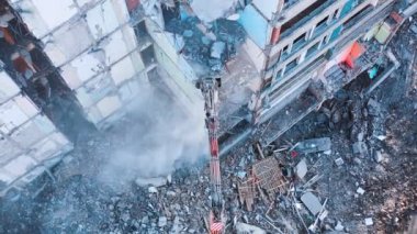 Makineleri yıkmak harabenin zeminini ve duvarlarını yıkar. Ağır tozlu bulutlarla enkaz dökülüyor. Harabeler ve molozlar üzerinde yükseliyor.