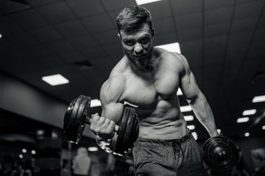 Spor salonunda üstsüz adam çalıştırmak. Güçlü kasları olan vücut geliştirici..