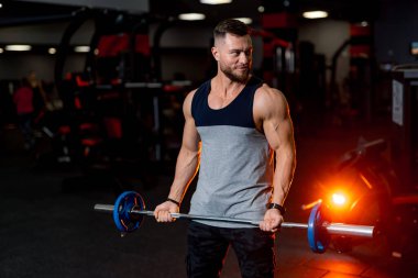 Spor salonunda çalışan yakışıklı bir antrenör. Vücut geliştirme tarzı güçlü erkek kişi.