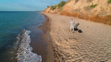 Genç adam mikrofona şarkı söylüyor. Sahilde şarkı söyleyen genç adamın hava manzarası.