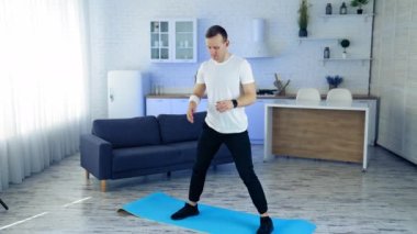 Evde fitness paspaslı bir adam var. Güçlü atletik formda adam evde egzersiz yapıyor.