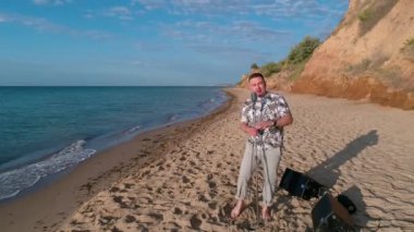 Adam mikrofona şarkı söylüyor. Genç adam plajda dururken mikrofona şarkı söylüyor.