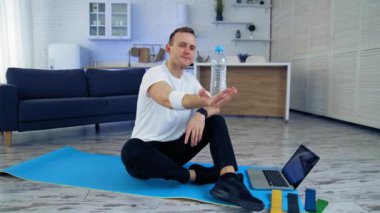 Evde egzersiz üstüne antrenman. Erkek sporcu evde online fitness yaptıktan sonra dinleniyor