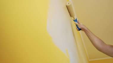 Odada duvar boyayan bir adam. Yeni apartman dairesinde, duvarları fırça silindiriyle boyayan adama yaklaş.