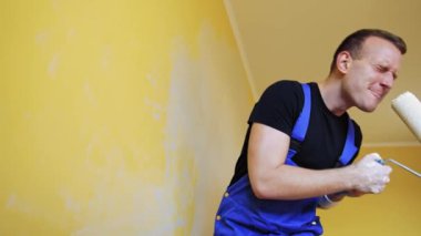 Boya fırçasında şarkı söyleyen adam. Duvarları boyayıp şarkı söyleyen neşeli adam.