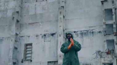 Harabelerin arasında gaz maskeli bir insan. Kıyamet sonrası ve harap bir şehirde yürüyen bir adam.