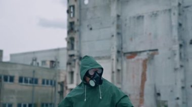 Atomik kazazede, kıyamet sonrası ortamında. Terk edilmiş binanın arka planında gaz maskeli bir adamın portresi.
