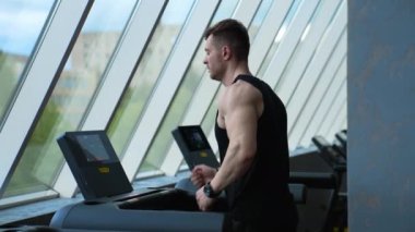 Koşu makinesinde antrenman yapan bir atlet. Spor salonundaki koşu bandında koşan genç adam.