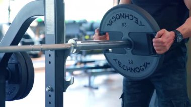 Spor salonunda antrenman yapan kaslı bir adam. Spor salonunda halter kullanarak vücut geliştirme eğitimi.