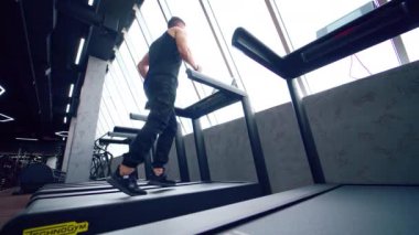 Spor salonunda koşan bir sporcu. Spor salonunda koşu bandında koşan formda bir adam.