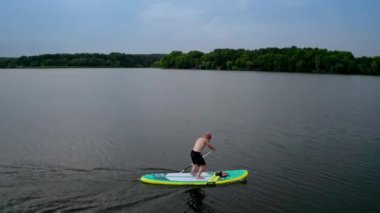 Yemek masasında duran adam. Su küreklerinde yakışıklı genç adam ayakta duruyor.