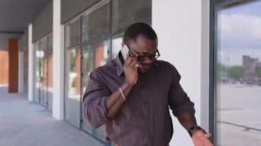 Siyah işadamı cep telefonu kullanıyor. İş adamı sokakta yürürken arıyor.