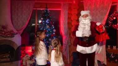 Çocuk için mutlu noel tatilleri. Noel Baba iki küçük kızla konuşuyor.