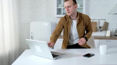 Genç adam dizüstü bilgisayar kullanıyor. Ev ofisinden laptopla çalışan bir iş adamı.