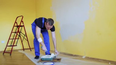 Daire dekorasyonu ve ev inşaatı. Tamirat sırasında tamircinin paten fırçasıyla duvar boyaması