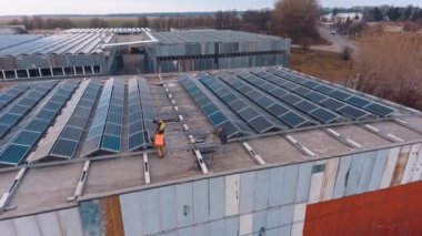 Güneş panelleri olan güçlü bir istasyon. Fotovoltaik panel sisteminin kurulumu ve bakımı üzerine çalışan işçilerin hava görüntüsü