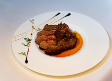 Üstünde et ve sos olan beyaz bir tabak.