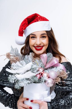 Noel Hediyesi Tutan Şenlikli Kadın. Noel Baba şapkalı bir kadın elinde Noel hediyesi tutuyor.