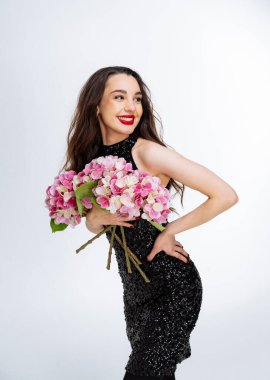 Siyah bir elbisenin zarafetini kucaklayan güzel bir kadın. Elinde bir buket çiçek tutan siyah elbiseli bir kadın.