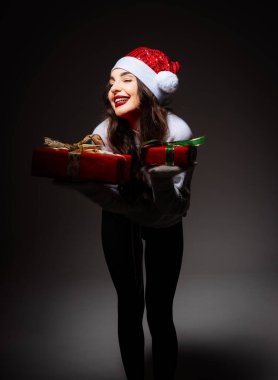 Kutlama Hediyesi Olan Neşeli Kadın. Noel Baba şapkalı bir kadın elinde hediye tutuyor.