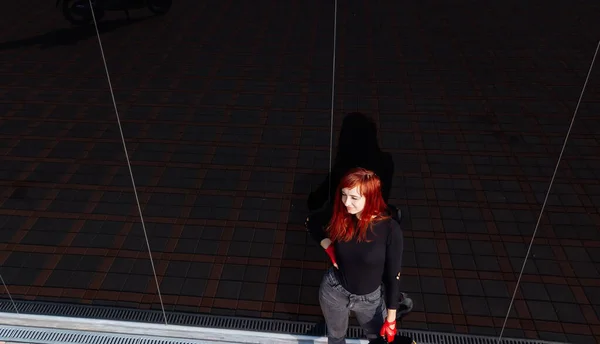A Woman Balancing on a Rope. A woman with red hair is standing on a rope