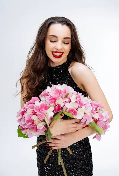 A Woman Holding a Beautiful Bouquet. A woman in a black dress holding a bouquet of flowers