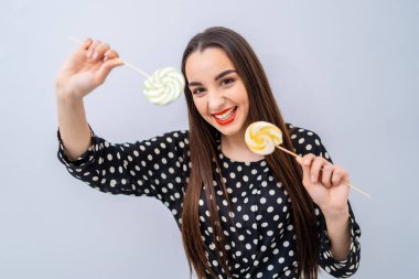 Bir kadın elinde lolipop tutuyor ve gülümsüyor.