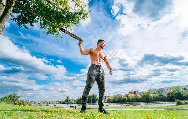 A Strong Man with a Baseball Bat. A shirtless man holding a baseball bat in a park
