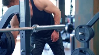 Genç adam spor salonunda çalışıyor. Sporcu adam spor salonunda halterle antrenman yapıyor.