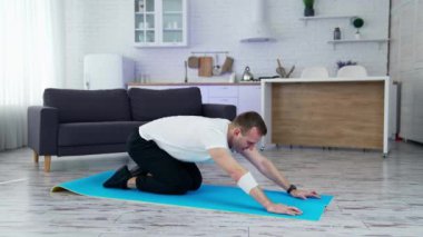 Yoga evde, minderde. Evde minderde yoga yapan bir adam.