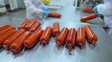 İşçiler sosis bağlıyor. İşçiler sosis yapmayı bitirir ve düzleştirirler.