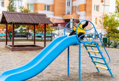 Küçük Çocuk, canlı bir Mavi Kaydırak 'ta Eğlenceli Yolculuk Yapıyor. Mavi bir slaytta oynayan küçük bir çocuk