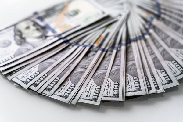 Пачки наличных на чистом белом столе. Куча денег сидит на белом столе