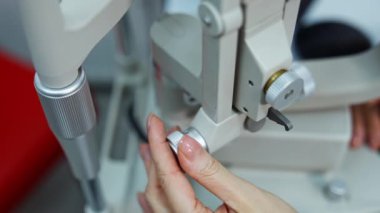Görme duyusunu kontrol etmek için bir cihaz. Optalmolojik cihazı özelleştiren bir doktorun kadın eli. Yakın plan..