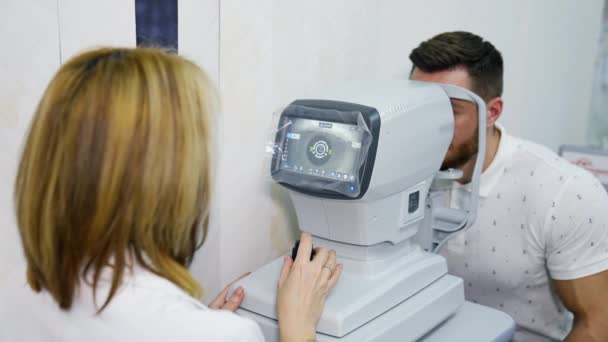 眼科医生在眼科诊所工作 女专家使用一种眼部生物显微检查仪器来检查一个成年男子的视力 — 图库视频影像
