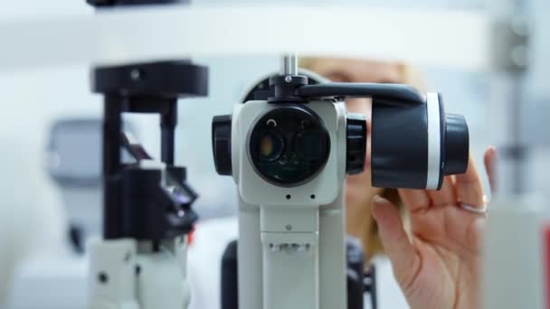 視力療法のための装置 医師は眼科センターで患者の目をチェックするためのデバイスをカスタマイズします 目のテストのための現代装置 クローズアップ — ストック動画
