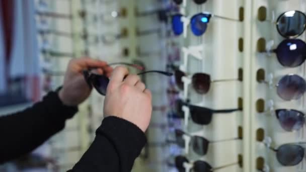 Modne Okulary Przeciwsłoneczne Stoisku Przy Optyce Człowiek Testujący Nowe Okulary — Wideo stockowe