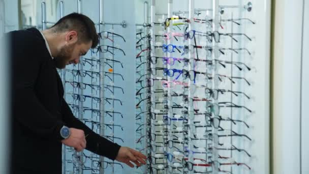 优雅的年轻人在寻找现代眼镜 男买主在光学商店选购新眼镜 眼镜的概念 — 图库视频影像