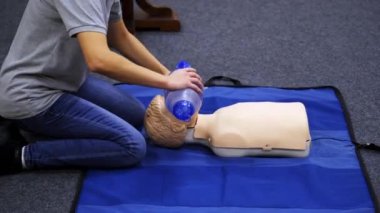Hayat kurtarmak için eğitim seansı. Eğitmen bir manken üzerinde kalp egzersizi gösteriyor. Solunum cihazı olan bir kuklanın suni teneffüs uygulaması.