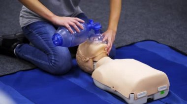 Kardiyopulmoner resüsitasyon. Eğitmen bir kuklanın üzerinde ilk yardım canlandırması gösteriyor. Sağlık çalışanı bir manken üzerinde kalp egzersizi gösteriyor..