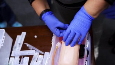 İğneyle yapılan pratik bir işlem. Öğrenci eğitim merkezinde kuklanın eline iğne batırma alıştırması yapıyor. Üst Manzara. Yakın plan..